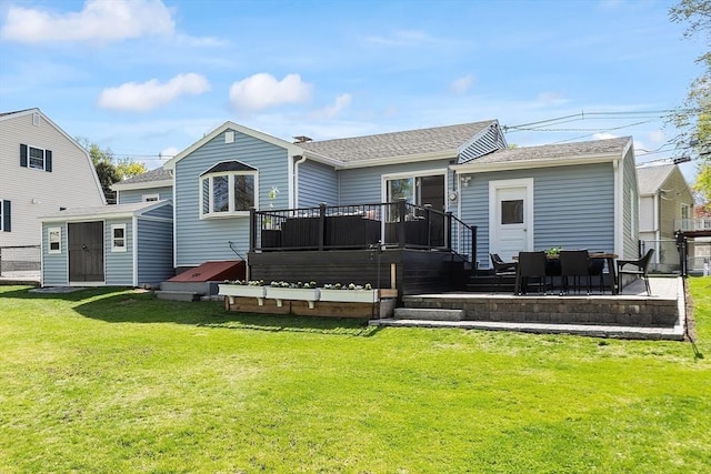back of property with roof with shingles, a yard, and a deck