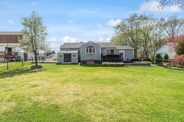 rear view of house with a fenced backyard, a yard, and a deck