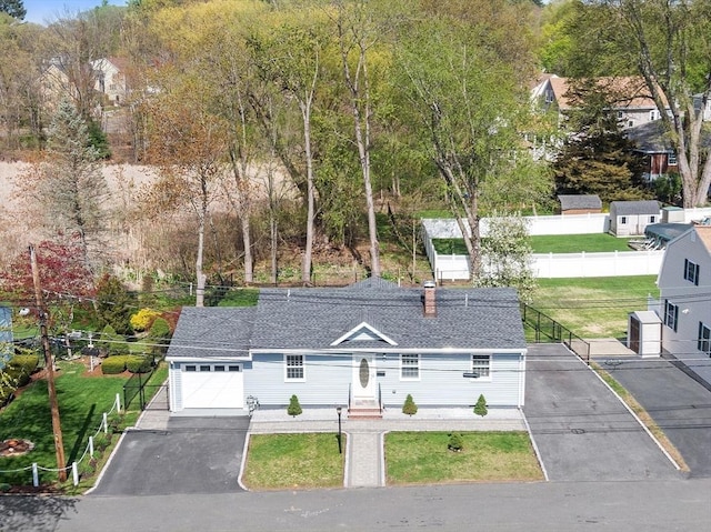 view of front of home featuring a chimney, roof with shingles, a garage, fence, and aphalt driveway