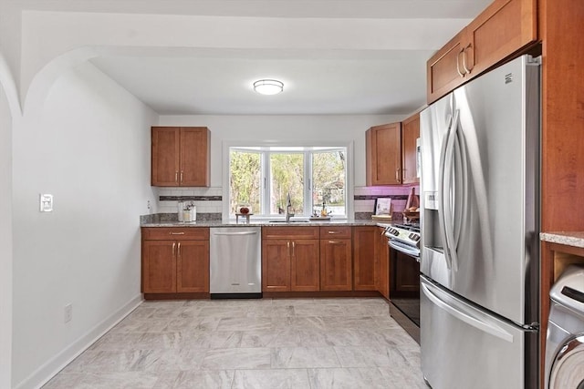 kitchen with washer / dryer, appliances with stainless steel finishes, decorative backsplash, and brown cabinetry