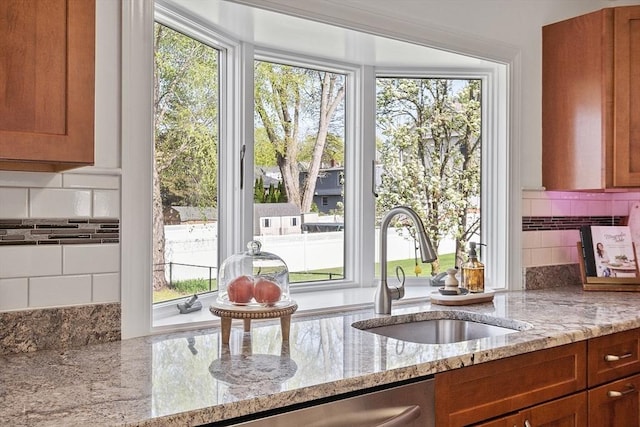 kitchen featuring backsplash, light stone counters, plenty of natural light, and a sink