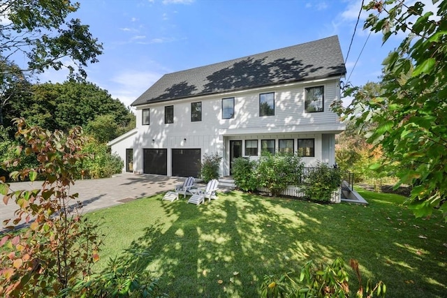 rear view of house featuring a garage and a yard