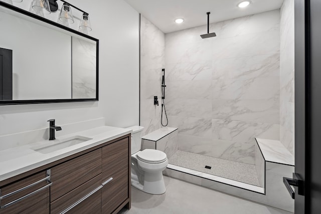 bathroom featuring toilet, vanity, and tiled shower