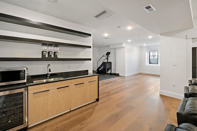 bar featuring wine cooler, sink, light brown cabinets, and light wood-type flooring