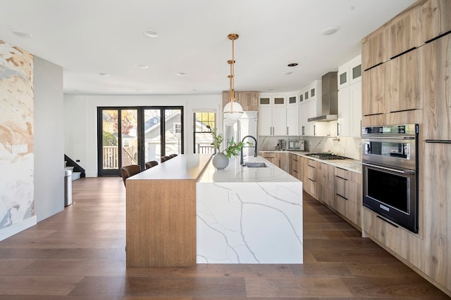 kitchen with dark hardwood / wood-style flooring, wall chimney exhaust hood, sink, white cabinets, and a large island