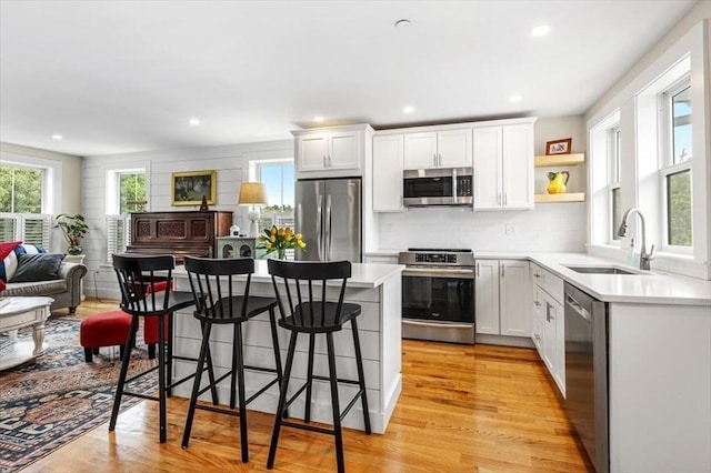 6 Macdonald Ter Unit E, Scituate, MA 02066 - kitchen with stainless steel appliances, a sink, a breakfast bar area, light wood-type flooring, and light countertops