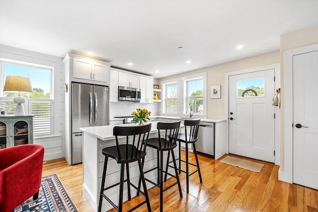 6 Macdonald Ter Unit E, Scituate, MA 02066 - kitchen featuring appliances with stainless steel finishes, light wood-type flooring, a breakfast bar, white cabinetry, and light countertops