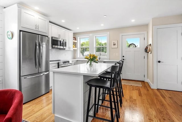 6 Macdonald Ter Unit E, Scituate, MA 02066 - kitchen with appliances with stainless steel finishes, a breakfast bar, light wood-type flooring, light countertops, and recessed lighting