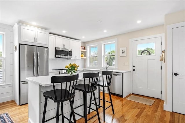 6 Macdonald Ter Unit E, Scituate, MA 02066 - kitchen featuring appliances with stainless steel finishes, a kitchen bar, light countertops, white cabinetry, and light wood-style floors