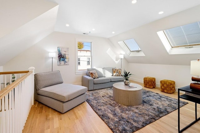 living room featuring vaulted ceiling with skylight and light wood-type flooring