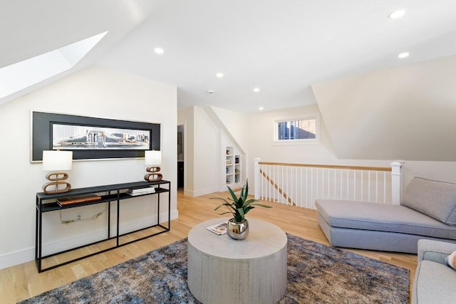 living room with lofted ceiling with skylight and light wood-type flooring