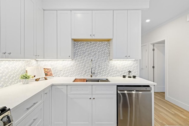 kitchen with tasteful backsplash, white cabinetry, sink, stainless steel dishwasher, and light hardwood / wood-style floors