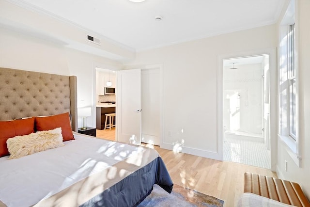 bedroom with crown molding, connected bathroom, light wood-type flooring, and a closet