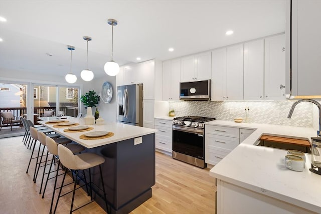 kitchen featuring appliances with stainless steel finishes, sink, pendant lighting, and white cabinets