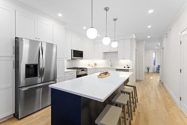 kitchen featuring white cabinetry, appliances with stainless steel finishes, a center island, and pendant lighting