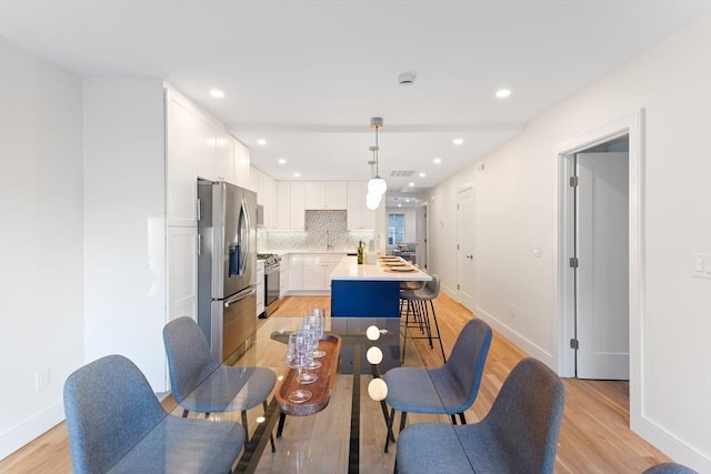 kitchen featuring white cabinetry, hanging light fixtures, a center island, light hardwood / wood-style floors, and stainless steel appliances