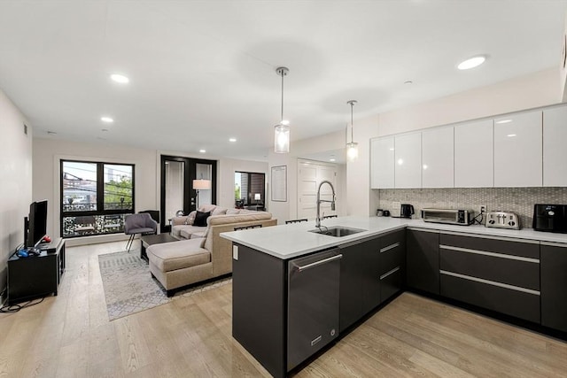 kitchen featuring sink, dishwasher, hanging light fixtures, white cabinets, and kitchen peninsula