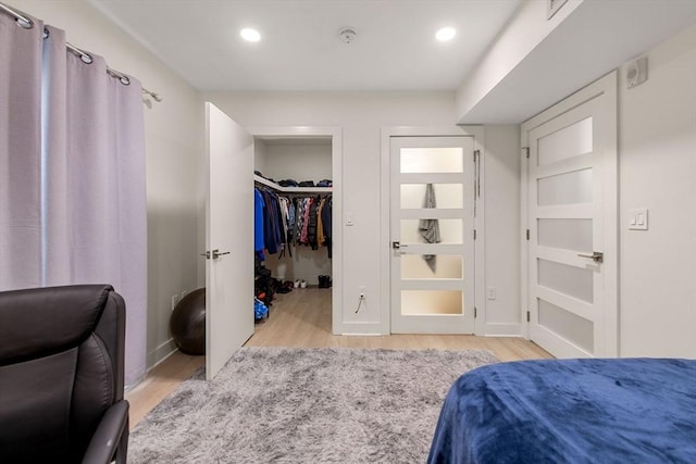 bedroom with a spacious closet and light hardwood / wood-style floors