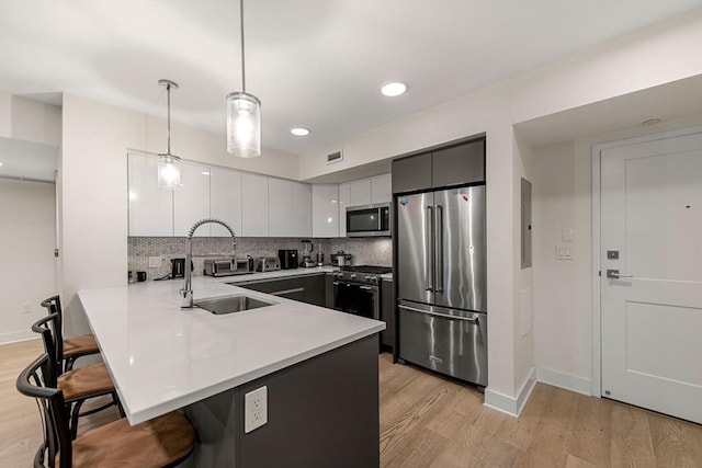 kitchen featuring light hardwood / wood-style flooring, a breakfast bar, hanging light fixtures, premium appliances, and kitchen peninsula