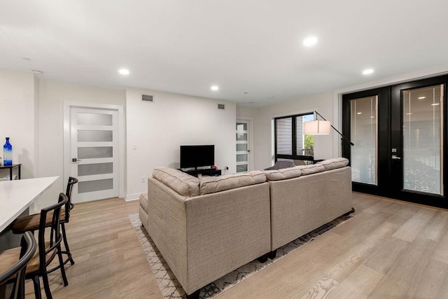 living room with built in shelves and light hardwood / wood-style floors