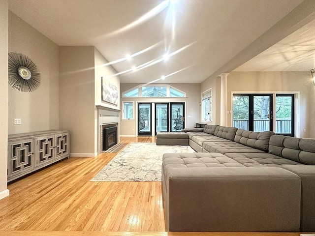 104 Channing Rd, Concord, MA 01742 - living area featuring light wood-style flooring, lofted ceiling, a fireplace with flush hearth, baseboards, and ornate columns