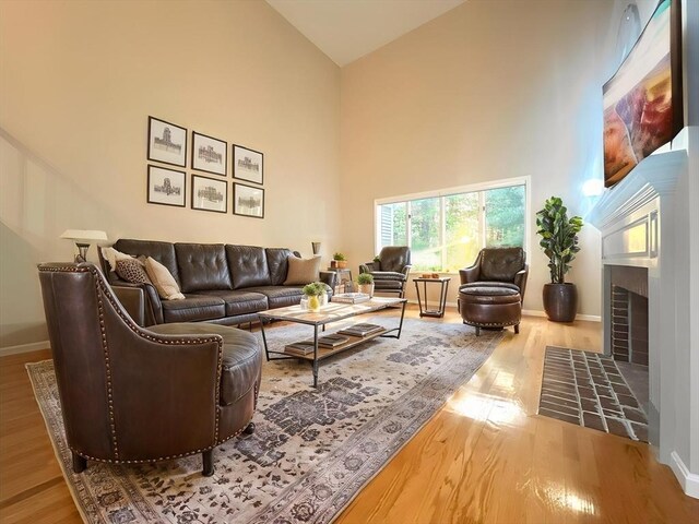 104 Channing Rd, Concord, MA 01742 - living area with a fireplace with flush hearth, high vaulted ceiling, wood finished floors, and baseboards