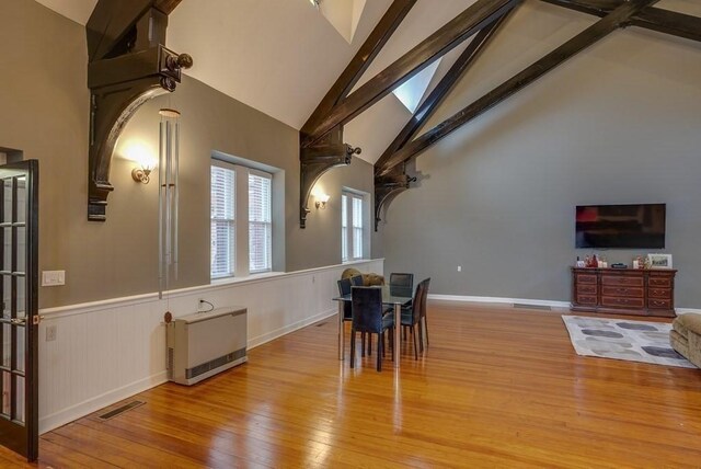 kitchen with sink, high vaulted ceiling, hardwood / wood-style flooring, tile countertops, and a breakfast bar