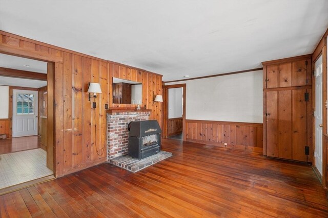 25 Charlotte Ave, Barnstable, MA 02635 - unfurnished living room featuring a wood stove, wood-type flooring, a wainscoted wall, and wood walls