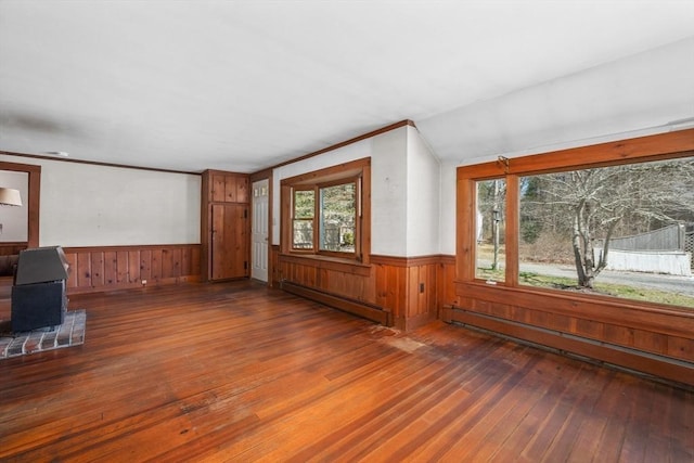25 Charlotte Ave, Barnstable, MA 02635 - unfurnished living room featuring wood walls, a baseboard heating unit, wainscoting, a baseboard radiator, and wood-type flooring