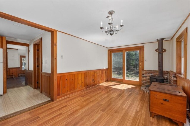 25 Charlotte Ave, Barnstable, MA 02635 - unfurnished dining area with a wood stove, light wood-style flooring, wainscoting, wooden walls, and a notable chandelier