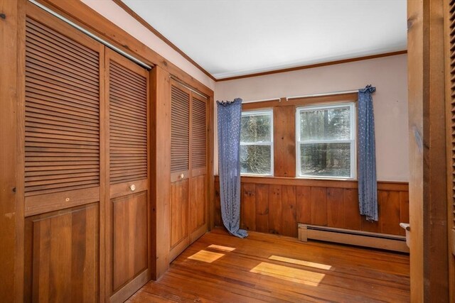 25 Charlotte Ave, Barnstable, MA 02635 - unfurnished bedroom with two closets, ornamental molding, hardwood / wood-style floors, wood walls, and a baseboard radiator