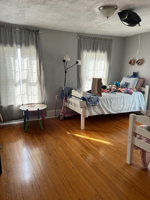 bedroom with a textured ceiling, hardwood / wood-style floors, and multiple windows