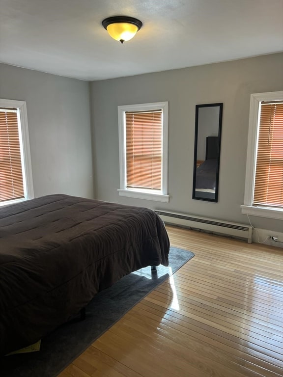 bedroom with light wood-type flooring and a baseboard heating unit