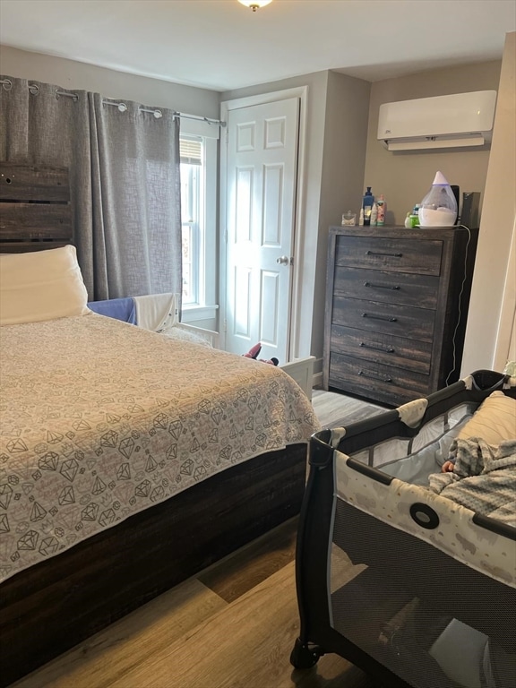 bedroom featuring a wall mounted AC and hardwood / wood-style flooring