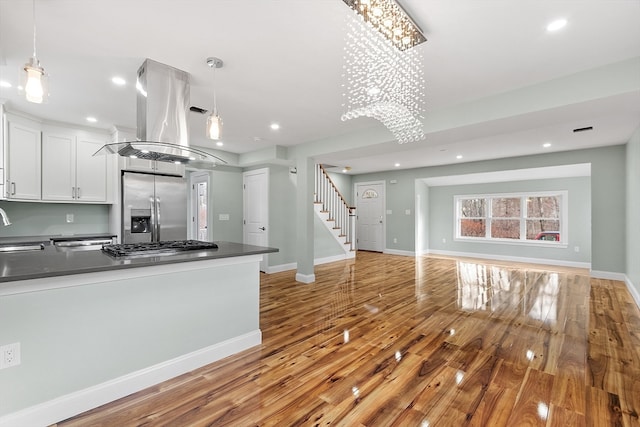 kitchen featuring hanging light fixtures, light hardwood / wood-style floors, white cabinetry, stainless steel appliances, and a chandelier