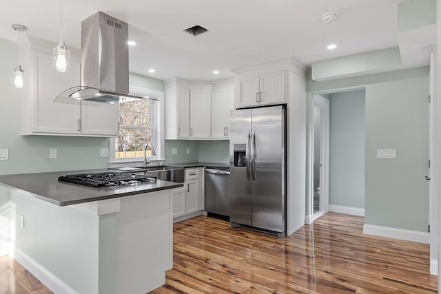 kitchen featuring light hardwood / wood-style flooring, decorative light fixtures, kitchen peninsula, island exhaust hood, and stainless steel appliances