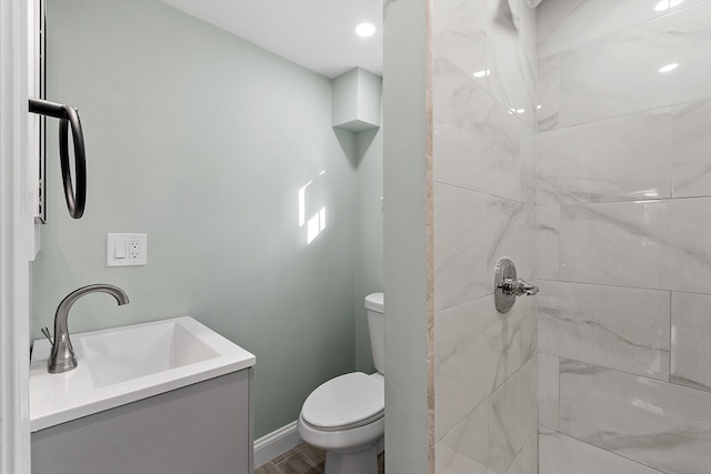 bathroom featuring tiled shower, toilet, wood-type flooring, and sink