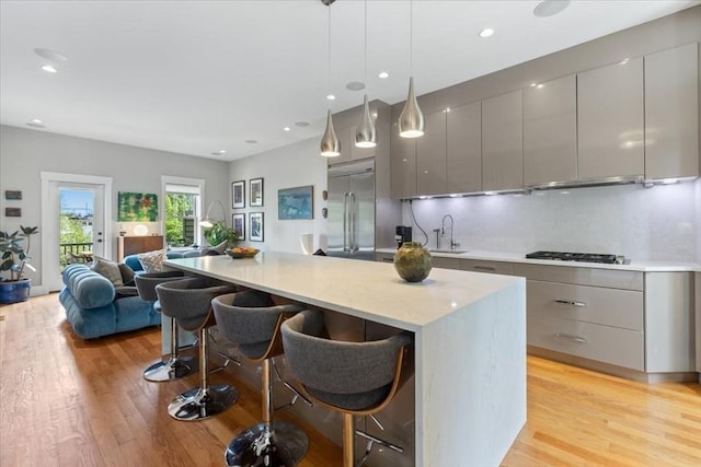 kitchen featuring stainless steel appliances, gray cabinets, modern cabinets, a breakfast bar area, and recessed lighting