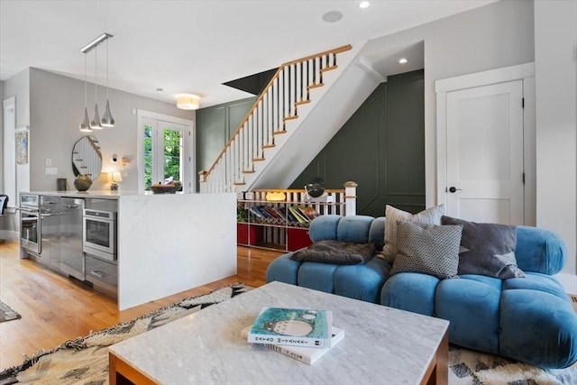 living area featuring stairway, light wood finished floors, and recessed lighting