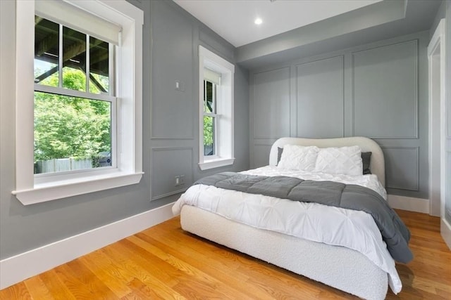 bedroom with baseboards, wood finished floors, and recessed lighting