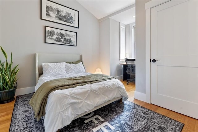 bedroom featuring wood finished floors, baseboards, and vaulted ceiling