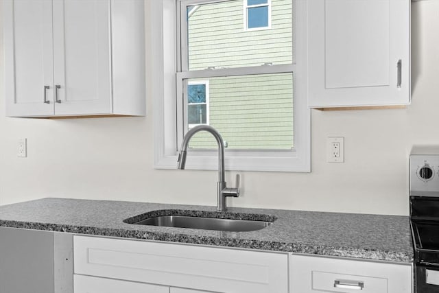 kitchen with sink, white cabinetry, dark stone countertops, and plenty of natural light