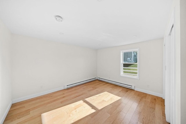 unfurnished room featuring baseboard heating and light wood-type flooring