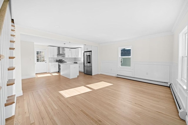 unfurnished living room featuring baseboard heating, plenty of natural light, and light wood-type flooring