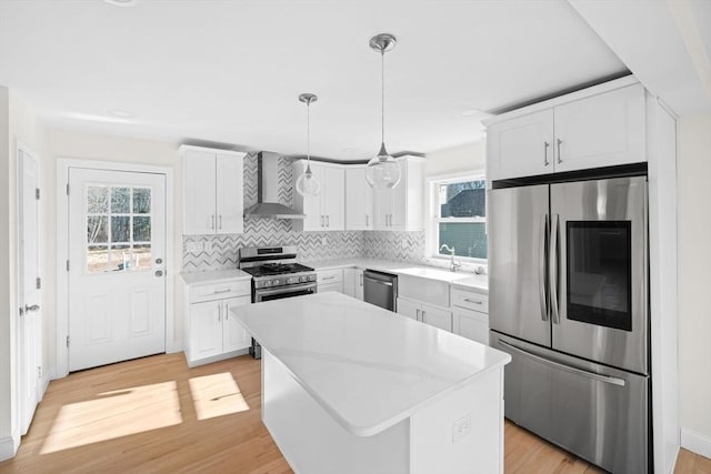 kitchen with a kitchen island, stainless steel appliances, white cabinetry, and wall chimney exhaust hood