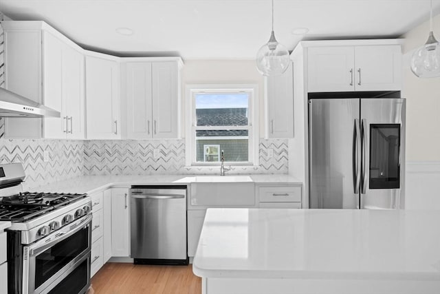 kitchen with stainless steel appliances, white cabinetry, light hardwood / wood-style flooring, backsplash, and hanging light fixtures