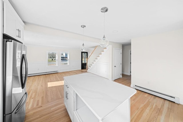 kitchen featuring decorative light fixtures, a baseboard radiator, white cabinetry, and stainless steel refrigerator