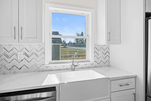 kitchen featuring sink, white cabinets, dishwasher, and light stone countertops