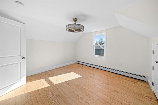 additional living space with light hardwood / wood-style flooring, lofted ceiling, and a baseboard heating unit