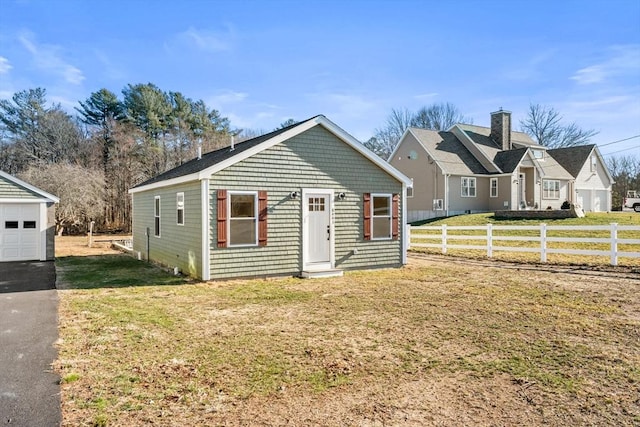 view of front of home with a front yard, a garage, and an outbuilding